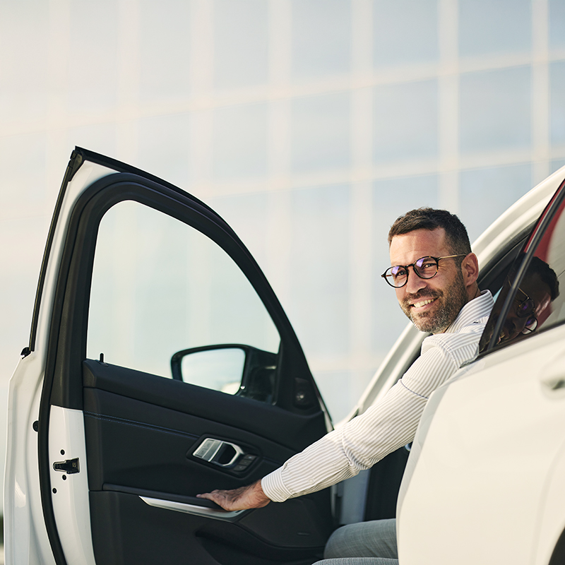 Happy businessman opening the car door on the street.