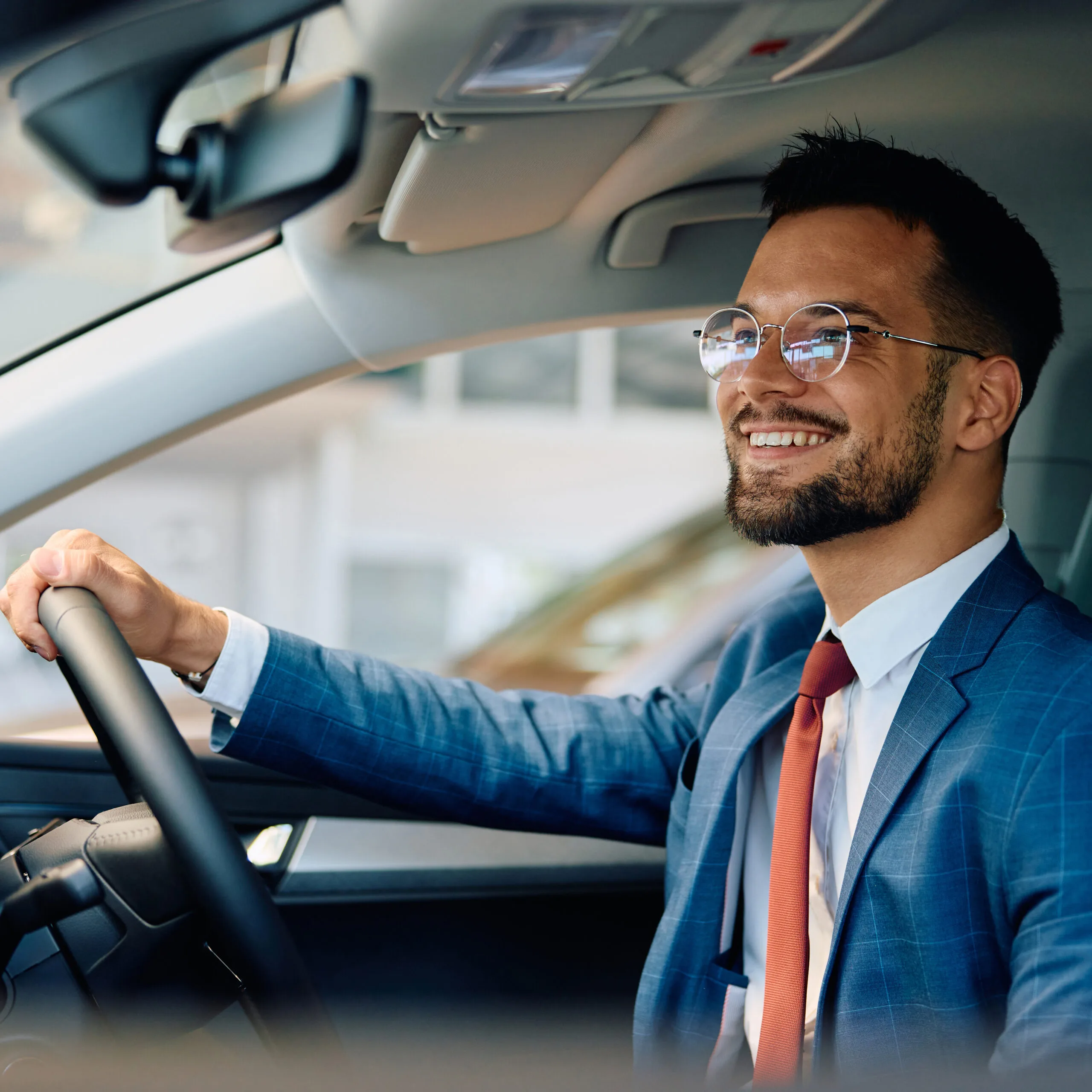 Young happy businessman testing new car in a showroom.